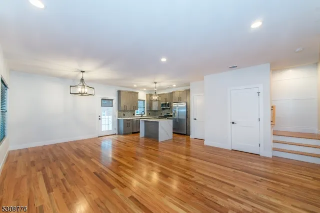 a view of a kitchen with kitchen island a sink wooden floor and a refrigerator
