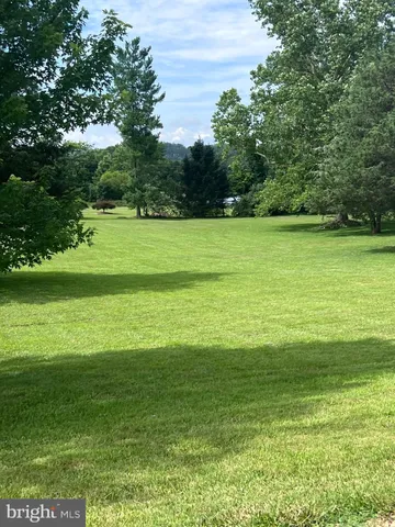 a view of a green field with wooden fence