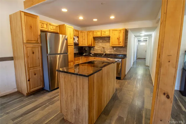 a kitchen with stainless steel appliances granite countertop a refrigerator a sink and wooden cabinets