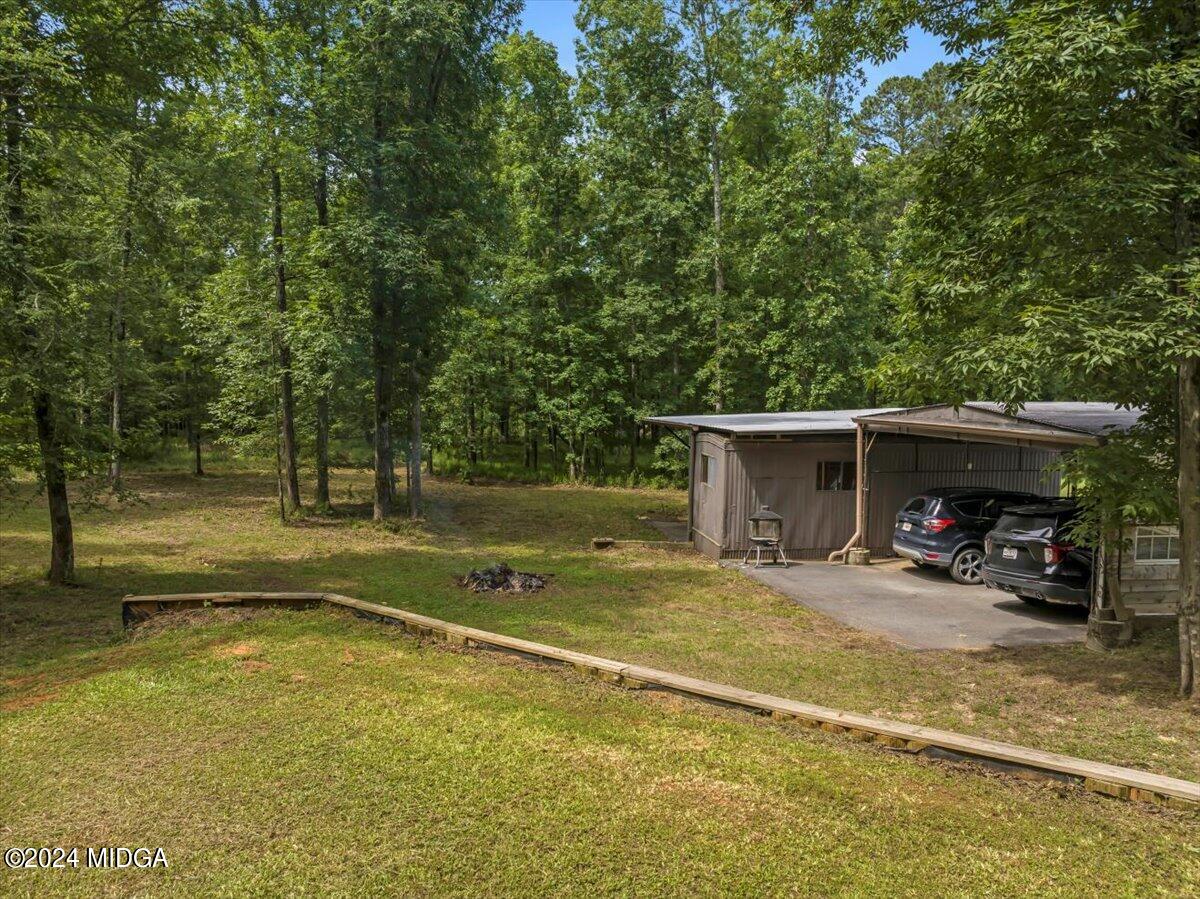 474 Plantation Road Gray, GA 31032 - Photo 62 of 64 a view of a wooden house with lawn chairs and a large tree