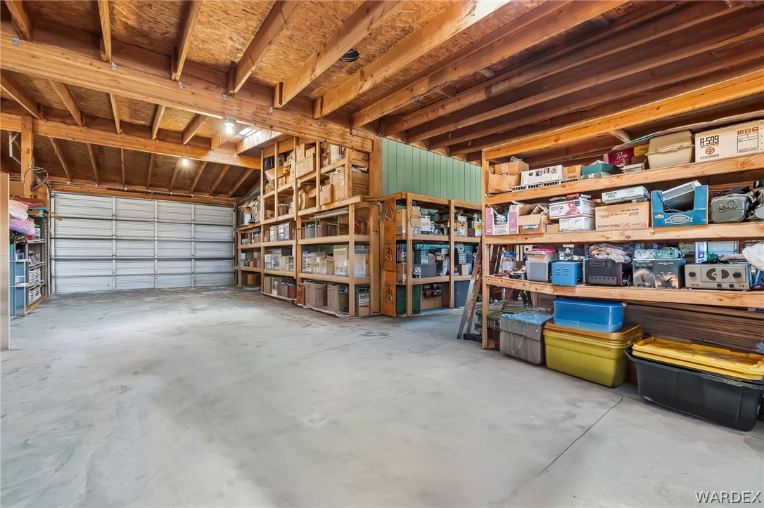2401 North Stephan Road Kingman, AZ 86401 - Photo 73 of 92 Spacious garage featuring a concrete floor, exposed wooden ceiling beams, and a roll-up garage door