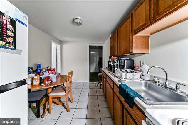 a kitchen with stainless steel appliances kitchen island granite countertop a dining table chairs a refrigerator and a sink