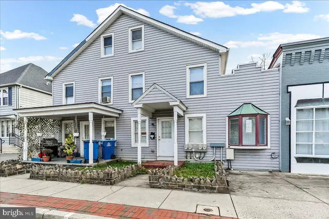 a view of a white house with large windows and flower plants