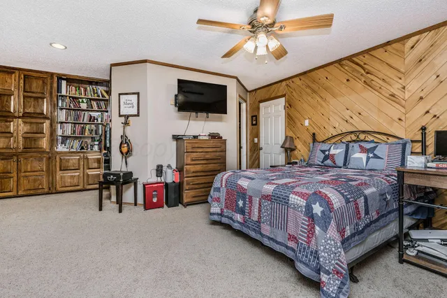 a bedroom with a bed a chandelier and a flat screen tv
