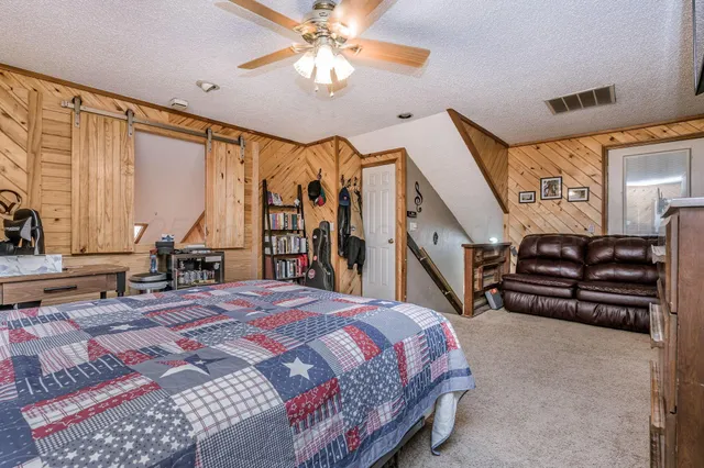 a bedroom with a bed dresser and a large window