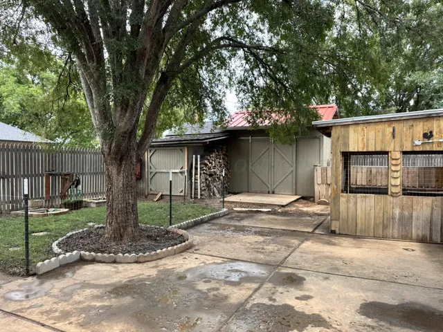 a view of a house with large tree and wooden fence