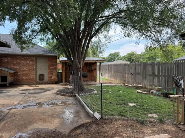 a backyard of a house with lawn chairs and a large tree