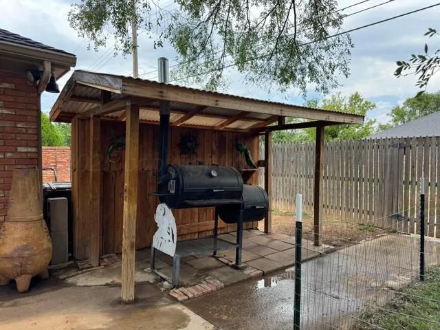 a view of a patio with table and chairs under an umbrella with wooden fence