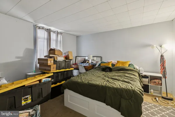 a spacious bedroom with a bed a desk and chair with the wooden floor