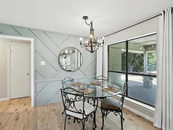 a dining room with wooden floor a glass table and chairs