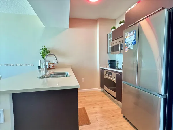 a kitchen with stainless steel appliances a refrigerator a sink and white cabinets