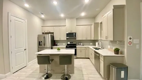 a kitchen with a sink chairs and refrigerator