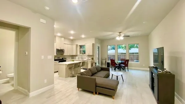 a living room with furniture kitchen area and a large window