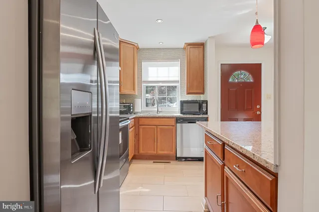 a kitchen with granite countertop a refrigerator stove top oven and sink