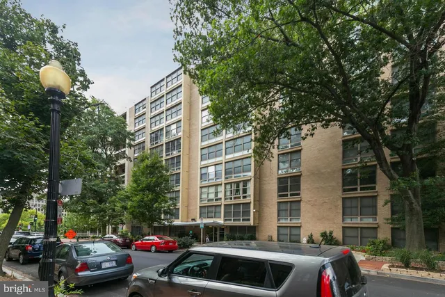 a front view of a building with cars parked