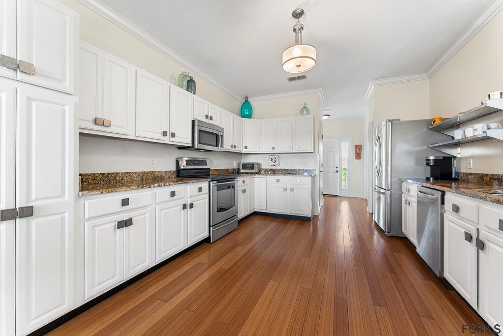 7619 A1A South St. Augustine, FL 32080 - Photo 12 of 51 a kitchen with white cabinets a sink dishwasher and a stove with wooden floor