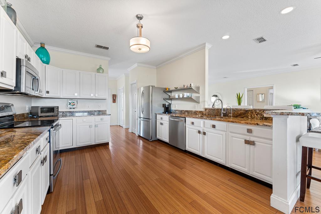 7619 A1A South St. Augustine, FL 32080 - Photo 13 of 51 a kitchen with stainless steel appliances sink cabinets and wooden floor
