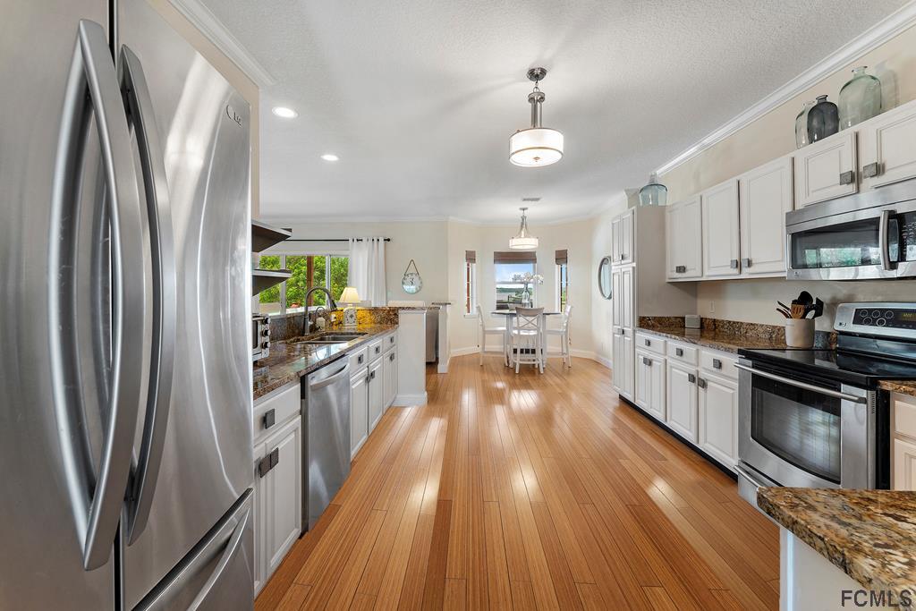 7619 A1A South St. Augustine, FL 32080 - Photo 14 of 51 a large kitchen with stainless steel appliances a refrigerator a stove a sink dishwasher a oven with white cabinets and wooden floor