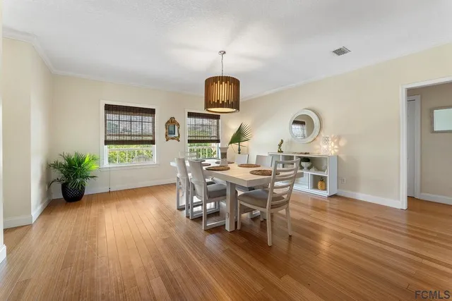 a dining room with wooden floor a chandelier a glass table and chairs