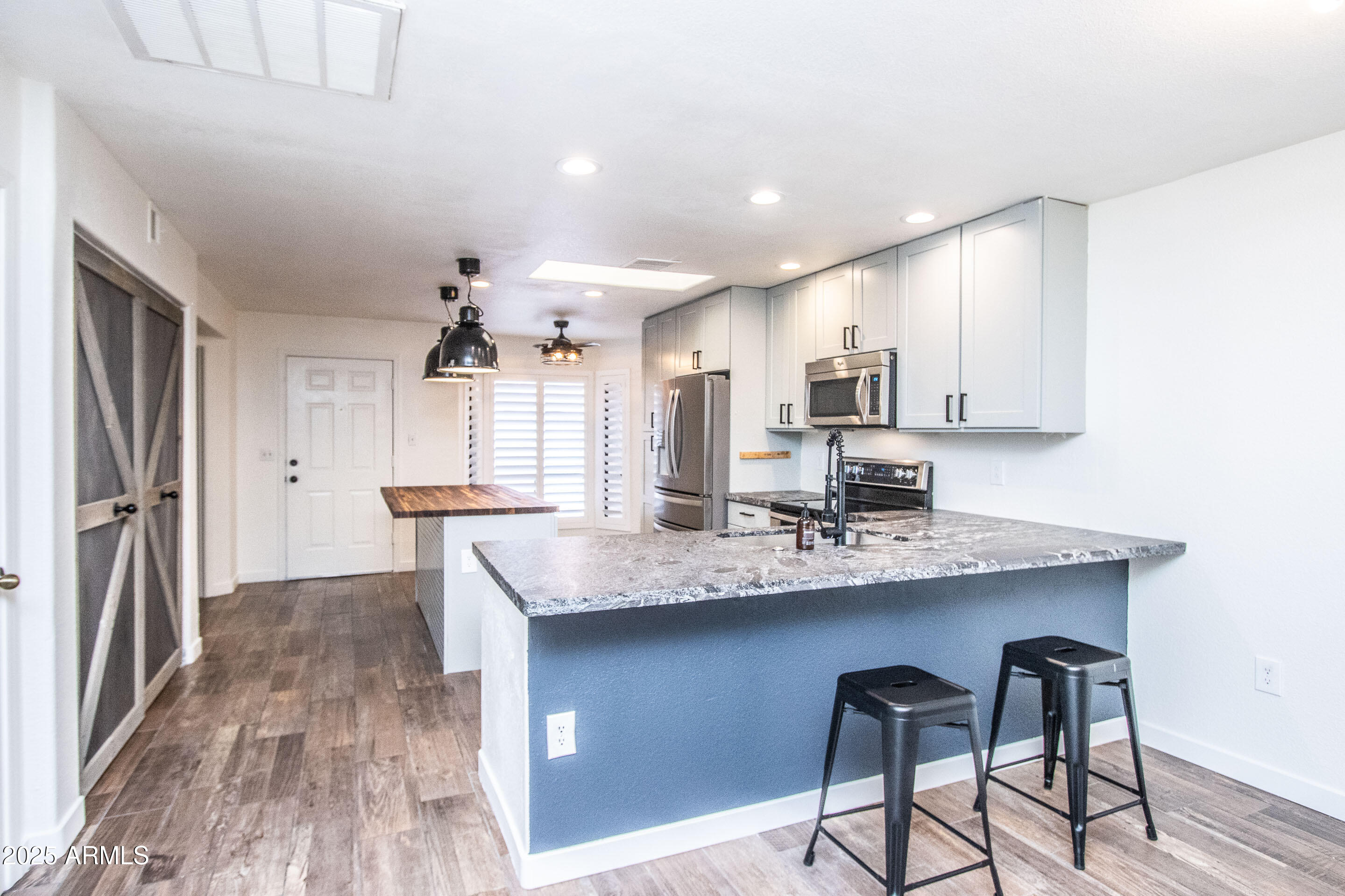 1318 East Cobb Drive Tempe, AZ 85288 - Photo 16 of 43 a kitchen with stainless steel appliances kitchen island granite countertop a table chairs in it and wooden floors