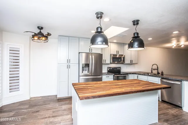 a kitchen with stainless steel appliances kitchen island granite countertop a refrigerator and a sink