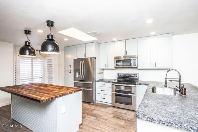 a kitchen with stainless steel appliances a kitchen island hardwood floor and a sink