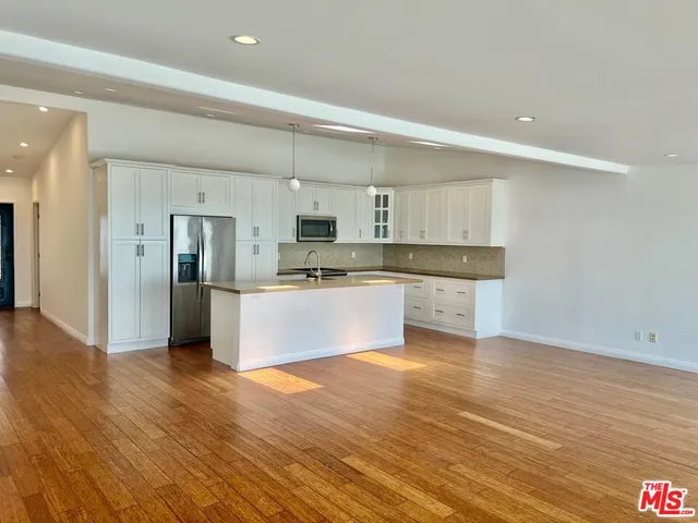 a view of kitchen with granite countertop cabinets and refrigerator