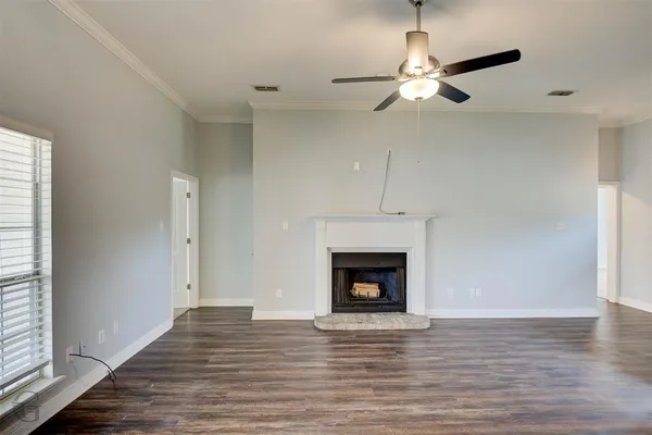 a view of an empty room with wooden floor fireplace and a window