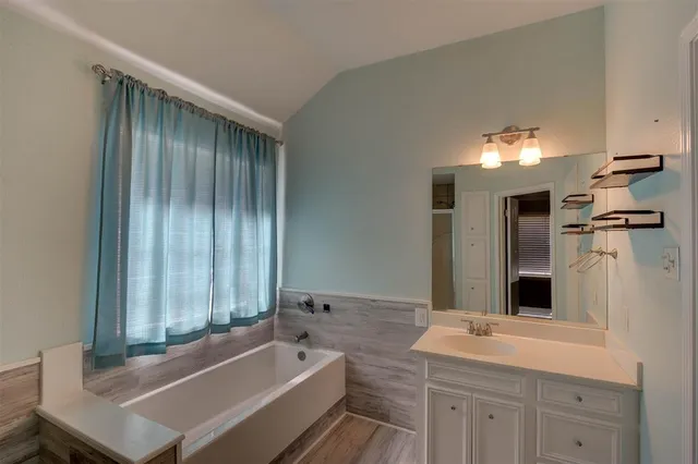 a bathroom with a tub sink and mirror
