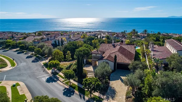 an aerial view of ocean and residential houses with outdoor space