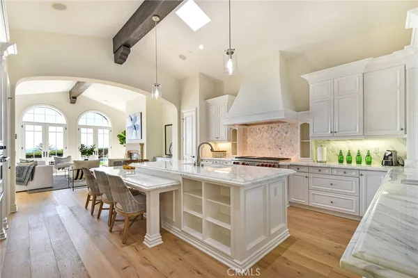 a kitchen with stainless steel appliances a stove a sink dishwasher and white cabinets with wooden floor