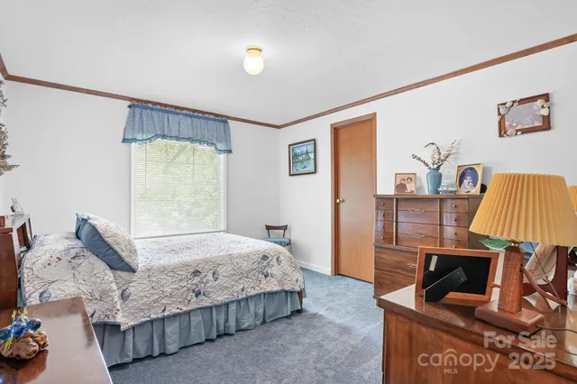a bedroom with a bed a couch and a flat tv screen on the dresser