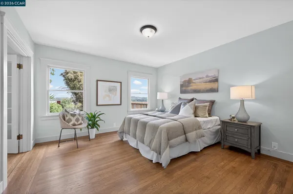 a spacious bedroom with a bed table chair and painting on the wall