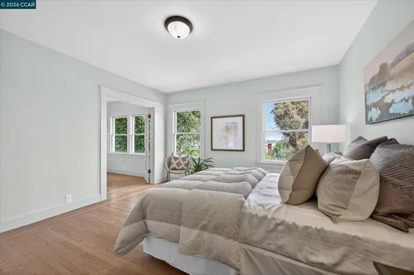 a large bed sitting in a bedroom next to a window and a wooden floor
