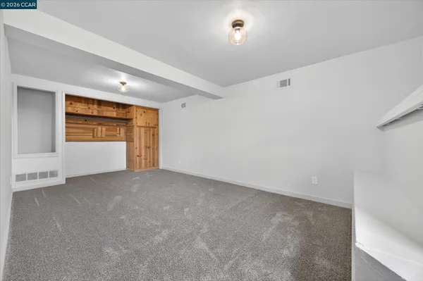 a view of an empty room with a window and fireplace