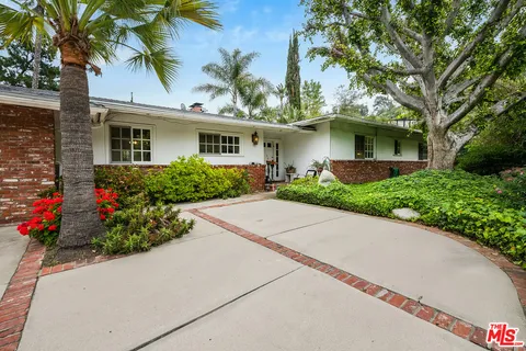 a front view of a house with a yard and potted plants