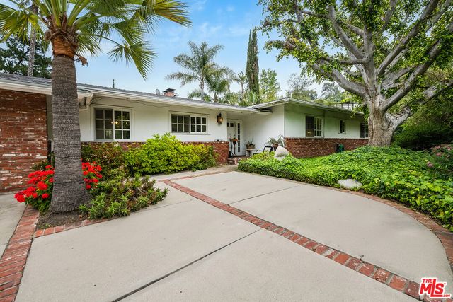 a front view of a house with a yard and potted plants