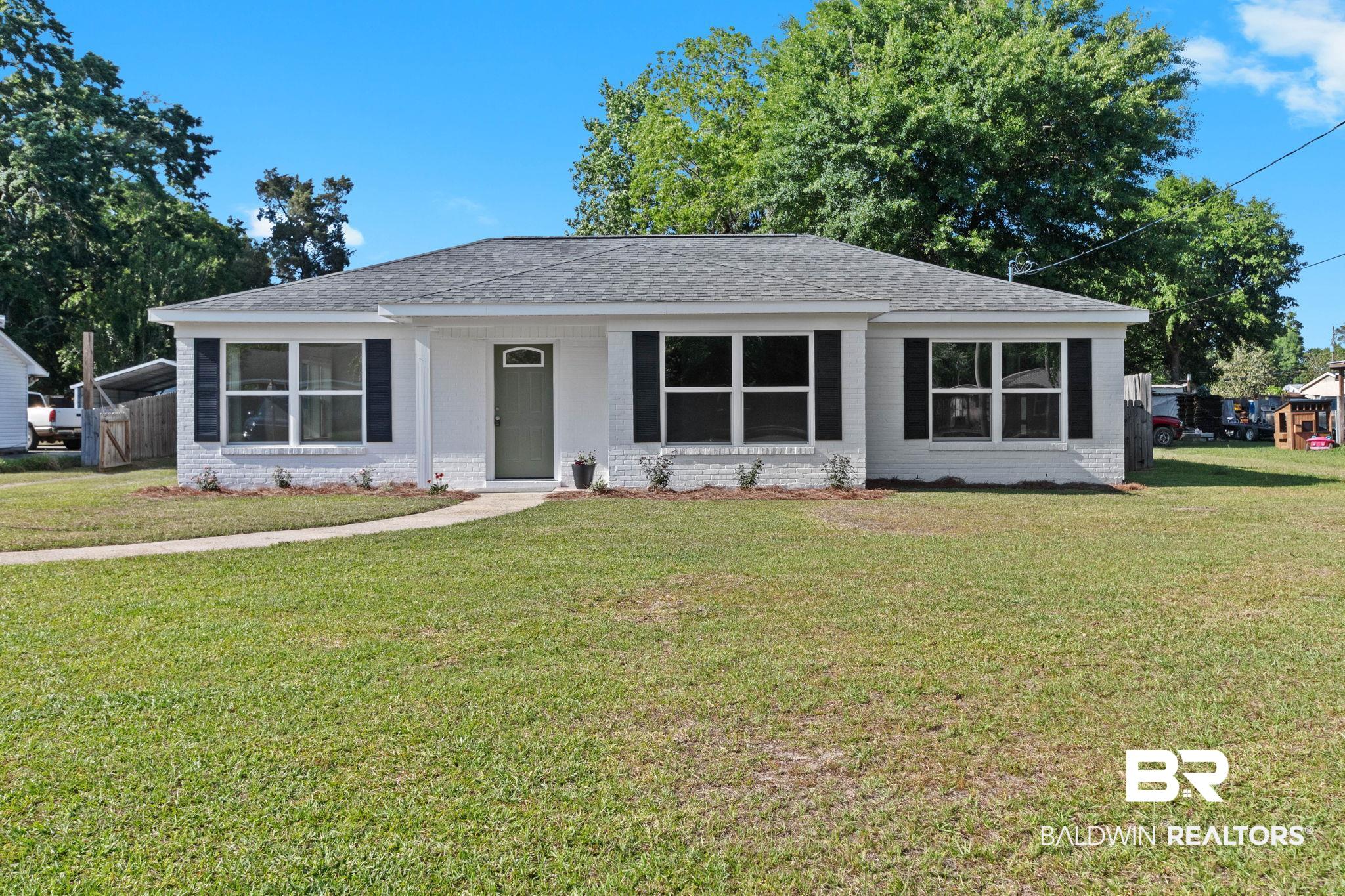 311 Cloverdale Road Atmore, AL 36502 - Photo 1 of 63 Single-story residence featuring white painted brick, a dark gray shingle roof, black louvered shutters, an arched entryway, and a curving concrete pathway