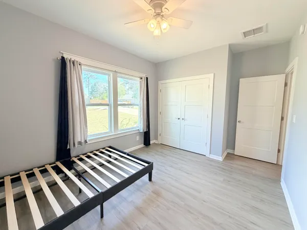 a large bed sitting in a bedroom next to a window and a chandelier