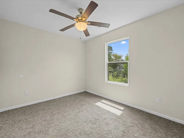 an empty room with a window and a fan