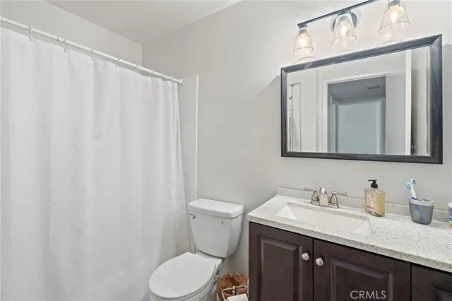 a bathroom with a granite countertop sink vanity mirror and toilet