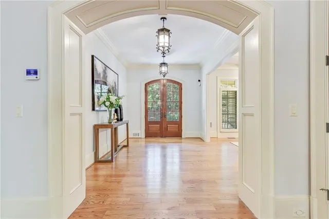 a hallway with wooden floor chandelier and entryway