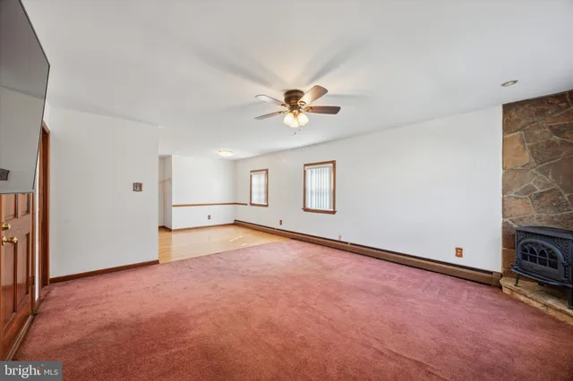 an empty room with chandelier fan and windows