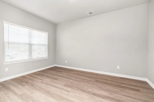 a view of an empty room with wooden floor and entryway