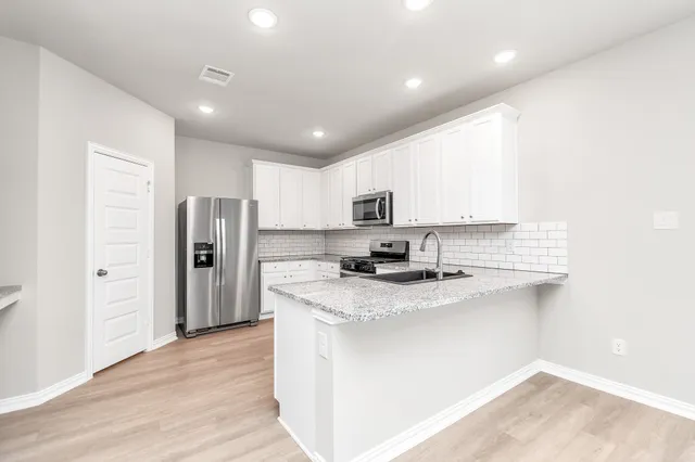 a large white kitchen with a refrigerator a sink and a stove
