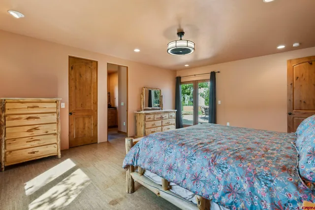 a spacious bedroom with a bed and a flat tv screen