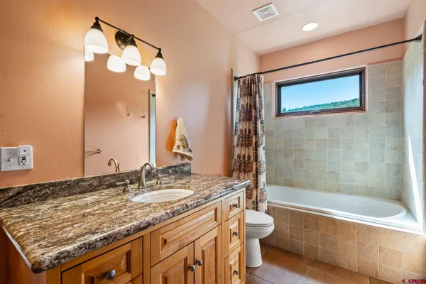 a bathroom with a granite countertop sink mirror toilet and bathtub