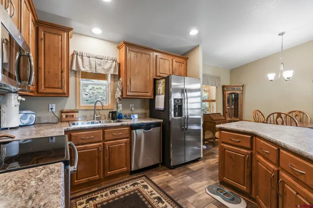 a kitchen with stainless steel appliances granite countertop a refrigerator a sink dishwasher a stove with wooden cabinets and floor