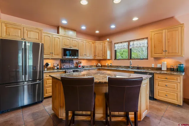 a kitchen with stainless steel appliances granite countertop a stove a sink a refrigerator a microwave and cabinets