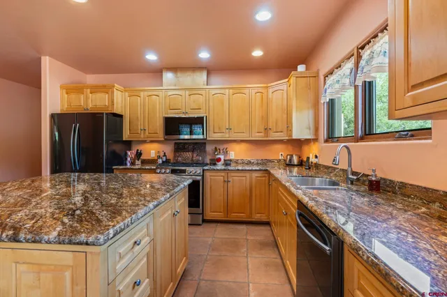a kitchen with stainless steel appliances granite countertop a stove refrigerator sink and microwave